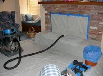 A fireplace sealed with dust sheets and a vacuum set up before sweeping